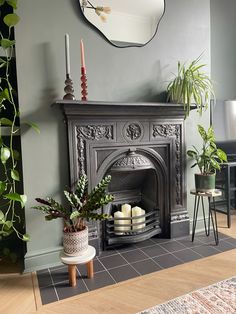 a living room with a fire place and potted plants on the table next to it