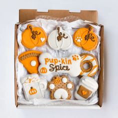 a box filled with lots of decorated cookies in different shapes and colors, including pumpkins