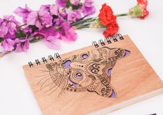 a wooden notebook with a drawing of a dog on it and some flowers next to it