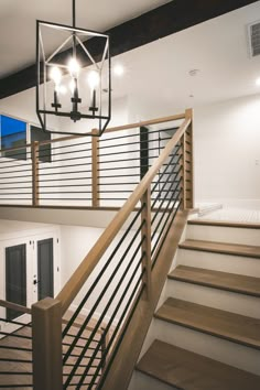 the stairs in this house are made from wood and metal, with chandelier above them