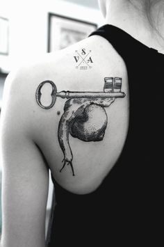 a black and white photo of a woman's shoulder with a key tattoo on it