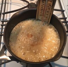 a pan filled with liquid sitting on top of a stove next to a thermometer