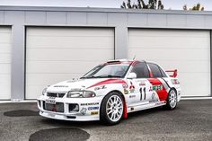 a white and red car parked in front of two garage doors