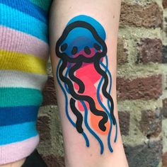 a woman with a tattoo on her arm has a colorful jellyfish design on it