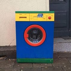 a blue and yellow washing machine sitting on the sidewalk