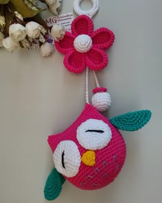 a crocheted owl ornament hanging from a string with flowers on it