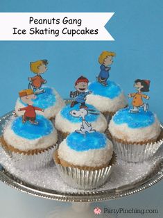 cupcakes with frosting and cartoon characters are on a silver platter next to a blue background