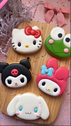 some hello kitty cookies are on a wooden board