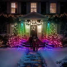 two people standing in front of a house decorated with christmas lights