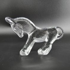 a glass horse figurine sitting on top of a table next to a black background