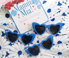 three blue heart shaped sunglasses sitting on top of a doily with a sign in the background