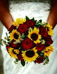 a bride holding a bouquet of sunflowers and red roses in her wedding dress