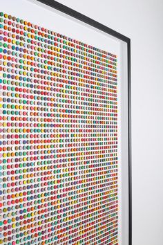 an art work is displayed on the wall in front of a white background with multicolored dots