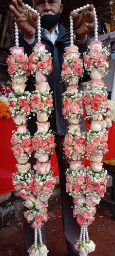 a man is holding flowers and beads in his hands