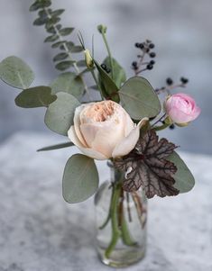 a vase filled with flowers and greenery sitting on top of a marble countertop