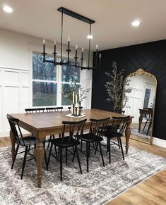 a dining room table with six chairs and a large mirror in the corner next to it