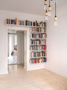 a book shelf filled with lots of books on top of a hard wood floor next to a doorway