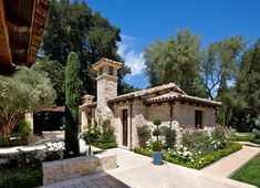 a stone house surrounded by trees and flowers