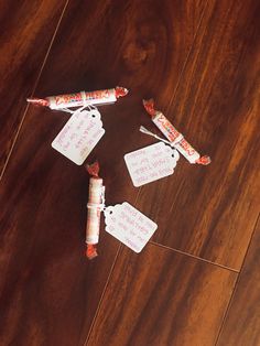 some candy sticks with tags on them sitting on a wooden floor next to each other