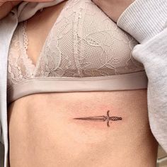 a woman's stomach with a small tattoo on her lower back and an arrow in the middle