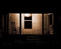 a rocking chair sitting on the front porch of a house in the dark at night