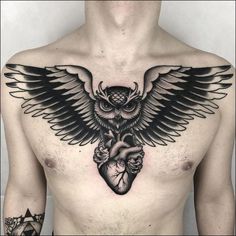 a man with an owl tattoo on his chest holding a heart and wings in front of him