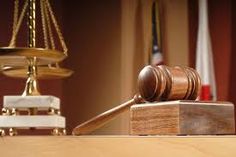 a wooden judge's gavel sitting on top of a table next to a scale