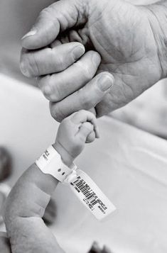 an older person holding a baby's hand with a name tag attached to it