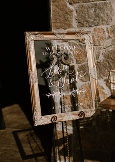 a sign that is sitting on top of a stand in front of a stone wall