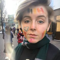 a young man with his face painted in different colors on the side of the street