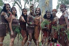 some people are dressed up and posing for a photo in front of a tree with white paint on their faces