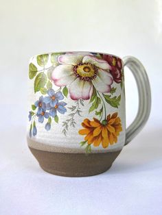 a coffee cup with flowers painted on the side and brown inside, sitting on a white surface