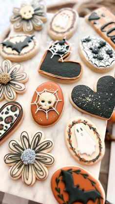 decorated cookies are arranged on a table with black and white decorations, such as bats, flowers, and hearts