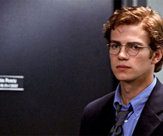 a young man wearing glasses and a suit