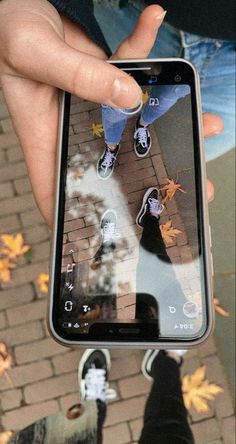 someone is holding up their cell phone to take a photo with the reflection of them