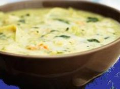 a brown bowl filled with broccoli soup on top of a blue table cloth