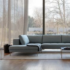 a couch sitting in front of a window on top of a hard wood floor next to a coffee table