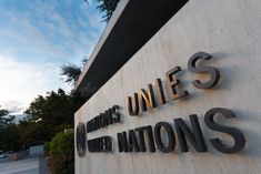 the united states and nations sign is shown in front of a building with trees on it