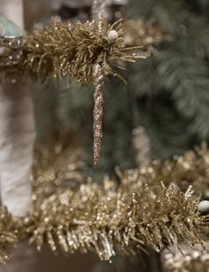 a close up of a christmas tree with gold tinsel and white balls on it