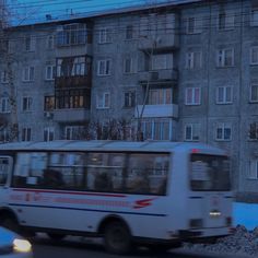 a bus is driving down the street in front of an apartment building at night time