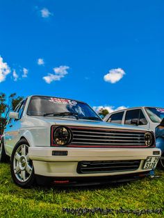 two cars parked in the grass on a sunny day