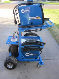 a blue machine is sitting on the sidewalk with its hoses attached to it's wheels