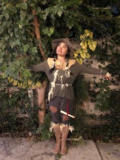 a woman dressed in costume standing next to a tree