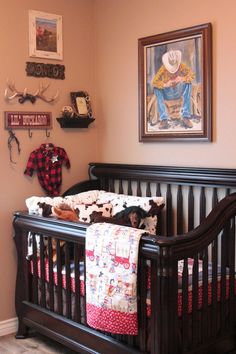 a baby's crib in the corner of a room with pictures on the wall