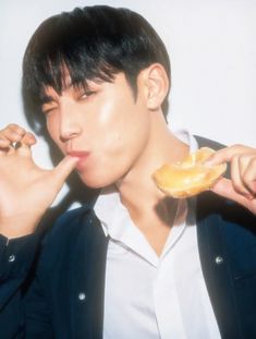 a man holding a donut in his right hand and biting it with both hands