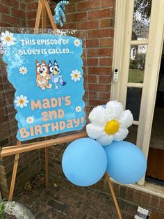 a birthday sign and balloons in front of a brick building with a blue door that says madi's 2nd birthday