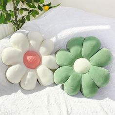 two flower shaped pillows sitting on top of a bed