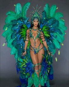 a woman in a green and blue costume with feathers on her head is posing for the camera