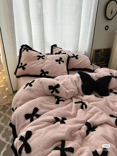 an unmade bed with black and white bows on it in front of a window