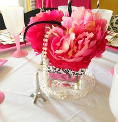 a pink flower in a vase sitting on top of a table next to a candle holder